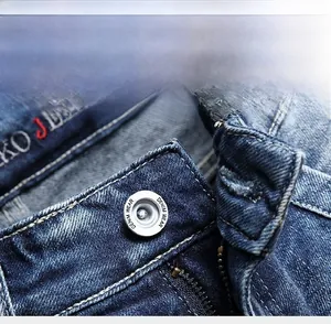 Detailed macro view of silver denim button and zipper on blue washed mid-waist jeans
