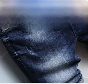 Detailed close-up of dark blue denim shorts featuring vintage whiskers and metal rivets