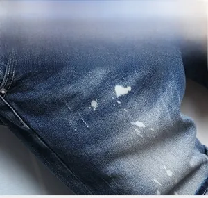 Close-up detail of blue denim shorts featuring vintage washed finish and white paint splatter