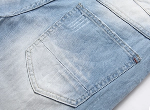 Macro detail of washed light blue denim shorts showing the pocket and orange stitching