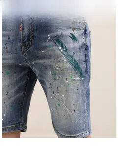 Détail macro du short en jean pour homme avec taches de peinture verte et accrocs