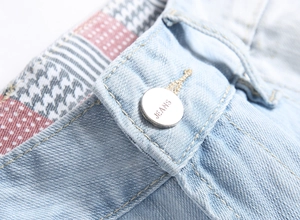 Macro shot of silver metal button engraved with JEANS and pattern waist lining detail