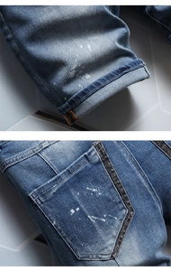 Detail view of blue denim shorts featuring heavy washing and white paint splatter accents