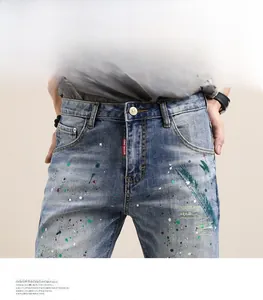 Détail du short en jean bleu avec éclaboussures de peinture et étiquette rouge brodée