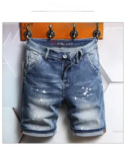 Detail view of light blue denim shorts with paint splatter effect and rolled hems