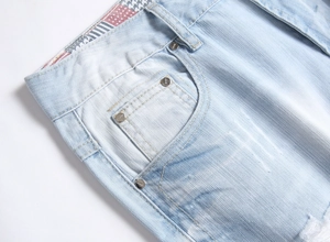 Detail of light blue denim fabric featuring silver metal rivets and quality stitching