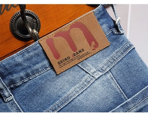 Detail of the brown leather waist patch and sewing on the washed blue denim shorts