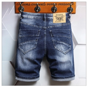 Detail of blue washed denim shorts featuring rear pockets and a brown leather designer patch