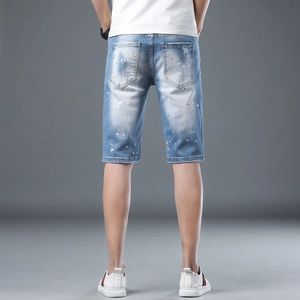 Men's light blue distressed denim shorts with colorful paint splatter and back pocket wear
