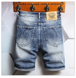 Detail of blue men's denim shorts showing vintage washed fabric and leather brand patch