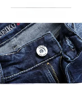 Detail display of metal button zipper and woven brand label on dark blue denim shorts
