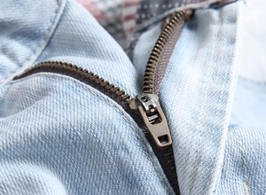 Macro detail of the metal zipper and blue denim texture on men's casual shorts