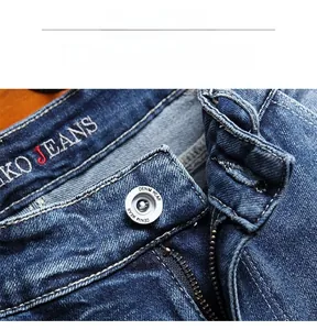 Detailed close-up of blue denim shorts featuring a vintage wash and branded metal button