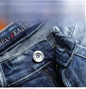 Detailed macro view of denim waist with metal button and zipper fly on blue jeans