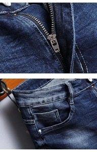 Detailed macro view of YKK zipper fly and front pocket stitching on blue washed denim shorts