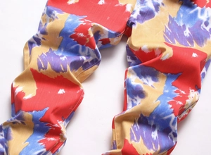Detailaufnahme der Slim Fit Hose mit abstraktem Camouflage-Muster in Rot Gelb Blau