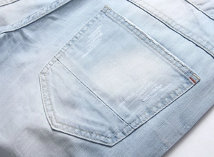 Detail of light blue denim shorts featuring ripped textures and double-stitched back pocket