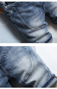 Macro shot of light blue washed denim jeans featuring curved stitching and metal rivets