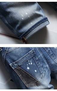 Detail view of denim shorts with white paint splatter and black patchwork pocket design