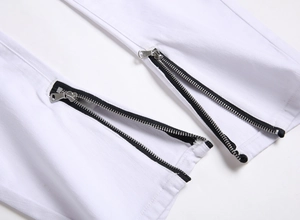 Macro detail of white slim-fit jeans featuring symmetrical silver ankle zippers on the hem