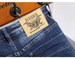Close-up of denim waist details featuring a brown designer leather patch and wash finish