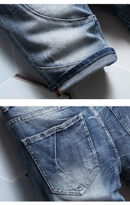 Detail of stitched hem and shield-shaped back pocket on washed blue denim shorts