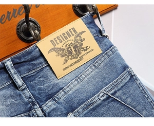 Detail of blue washed denim waist featuring a brown faux leather brand patch on back