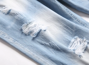 Detailed close-up of distressed denim shorts showing ripped texture and faded wash