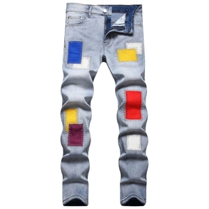 Detailed view of colorful patchwork and frayed edges on light blue men's denim jeans