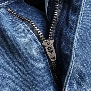 Close-up of high-quality YKK zipper on dark blue denim shorts with sturdy twill texture