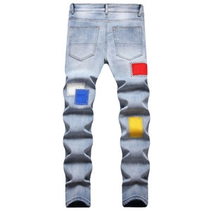 Detail of light blue slim fit jeans featuring colorful patchwork and decorative stitching