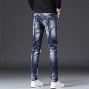 Gros plan d'un jean bleu pour homme avec détails usés, taches de peinture et poches arrière