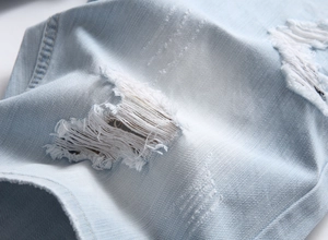Close-up of light blue denim shorts with distressed ripped detailing and cotton fabric texture
