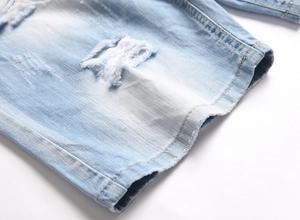 Close-up of light blue washed denim shorts featuring heavy distressed ripped details