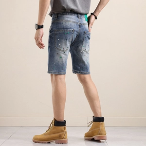 Short en jean bleu pour homme avec effet éclaboussures de peinture et écusson vert au dos
