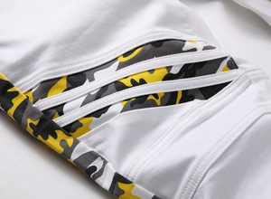 Détail du jean de motard blanc avec patchwork camouflage et coutures côtelées au genou