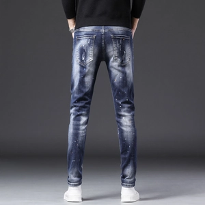 Détail de jean slim homme avec délavage intensif et éclaboussures de peinture colorées