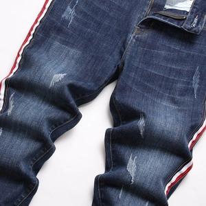 Jean bleu délavé pour homme avec des bandes latérales rouges et blanches sportives