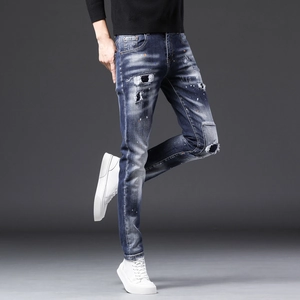 Détail du jean slim pour homme avec taches de peinture et patchs en denim tendance