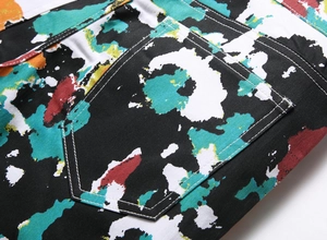 Close-up of denim pants featuring colorful graffiti paint splatter and rear patch pocket