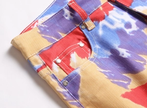 Detailaufnahme der bunten Batik-Denim-Stoffstruktur mit silbernen Nieten und feinen Nähten