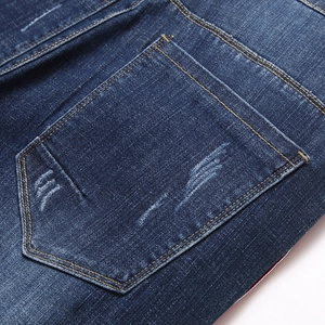Gros plan d'un jean bleu foncé pour homme avec poche arrière usée et coutures jaunes