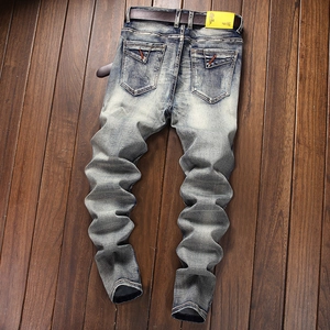 Detailed macro view of washed blue denim with vintage whiskers and a brown leather belt