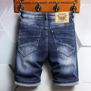 Men's blue washed denim shorts with whiskering, leather patch, and rolled cuffs