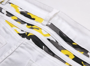 Détail de la taille d'un jean en sergé blanc avec bandes décoratives camouflage