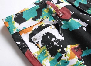 Detailed close-up of graffiti paint splatter print and metal rivets on denim jeans