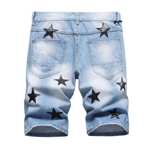 Men's light blue wash denim shorts with black leather star patches and raw edge hem
