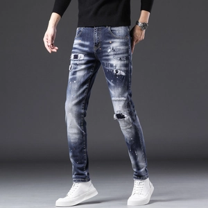 Détail du jean denim bleu délavé avec taches de peinture colorées et empiècements