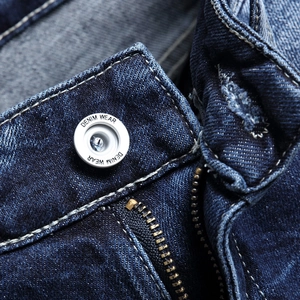 Men's blue washed denim shorts featuring metal zipper fly and branded button detail