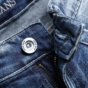 Close-up of mid-rise washed blue denim jeans with silver button and metal zipper detail